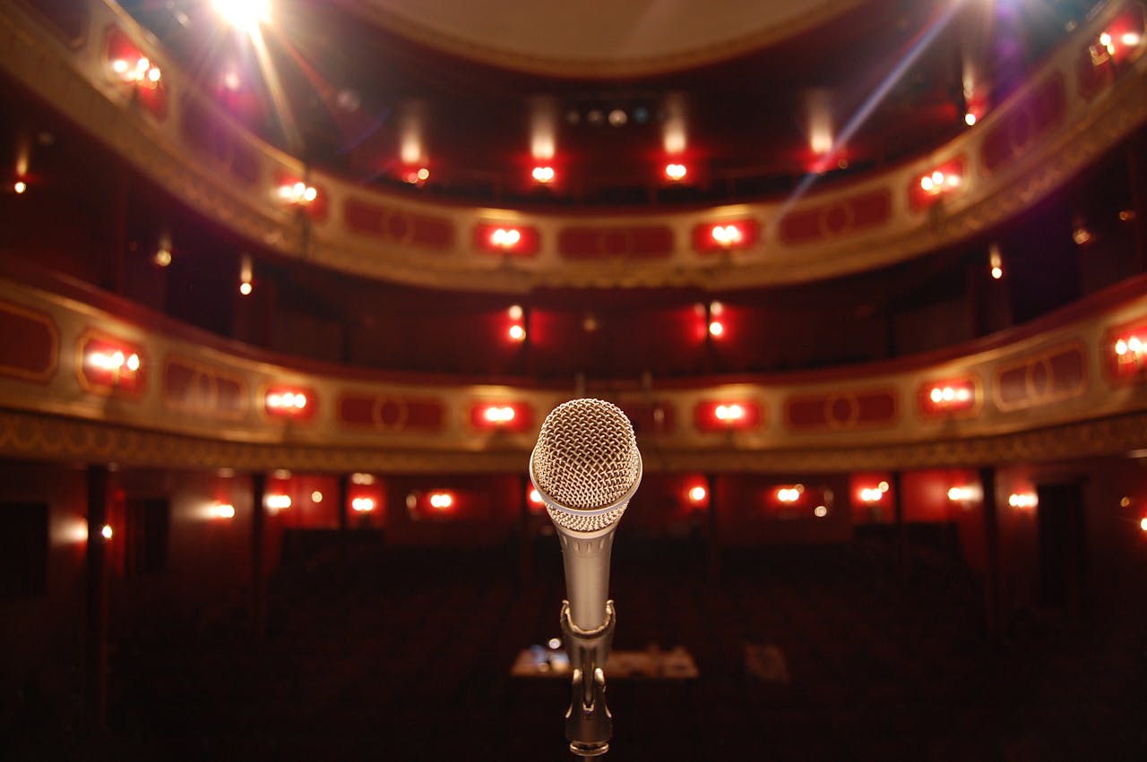 Mastering the First Impression: Your intriguing post title goes here A microphone stands on a theater stage with ornate balconies and warm lighting.