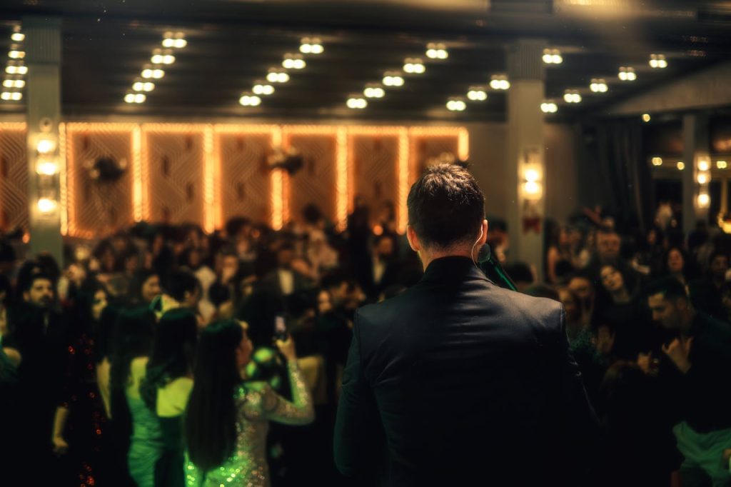 pexels photo 19466414 A crowded indoor night event with a man addressing the audience, vibrant lighting enhances the scene.